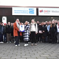 BBW-Schülerinnen und -Schüler sowie Lehrkräfte vor dem BBW-Hauptgebäude mit Plakette zum Deutschen Arbeitgeberpreis